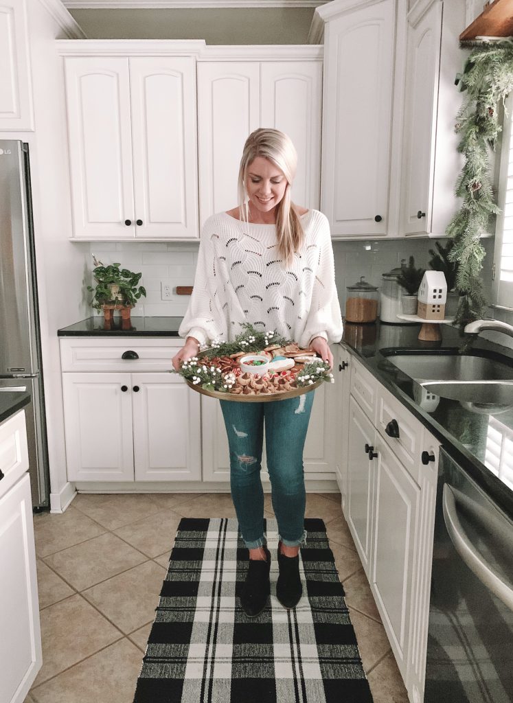 girl holding a tray full of Christmas treats on a tray in her kitchen